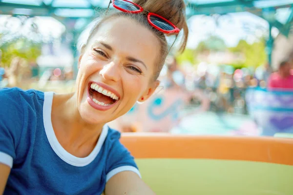 Happy modern traveller woman in theme park having ride — Stock Photo, Image