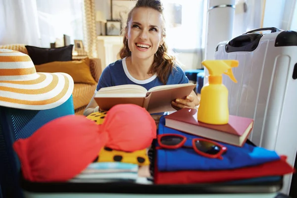 Tourist woman reading book in pause between preparing for trip — Stock Photo, Image