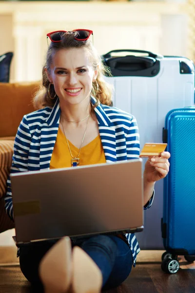 happy modern woman with credit card booking tickets on laptop