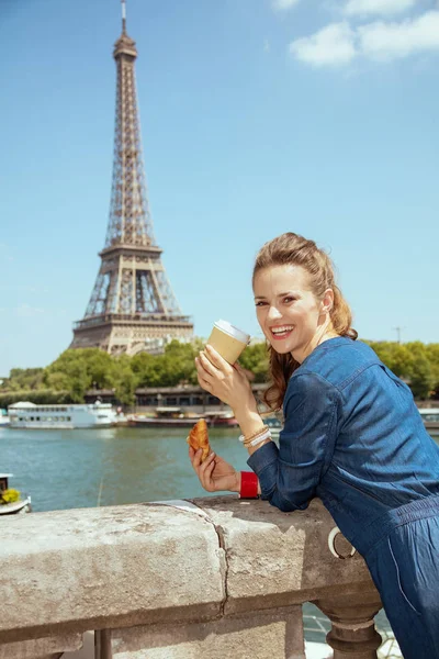 Woman with cup of coffee and croissant exploring attractions — Stock Photo, Image