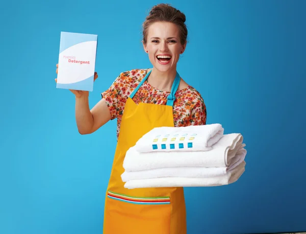 Усміхнена жінка з білим полотном, що показує порошковий миючий засіб на синьому — стокове фото