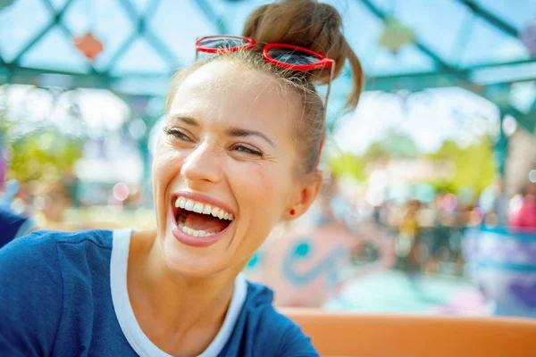 Sonriente mujer de moda en el parque de atracciones disfrutando de paseo — Foto de Stock