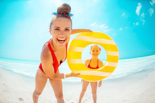 Feliz madre e hijo con boya inflable amarilla en la playa —  Fotos de Stock