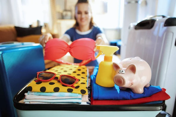 Closeup on happy woman with piggy bank calculates summer budget — Stock Photo, Image