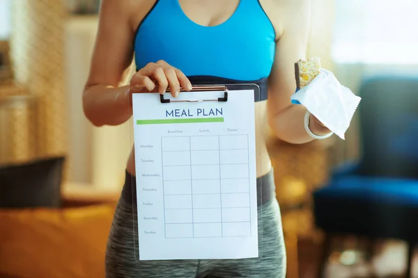 Primer plano de la mujer en forma con barra de energía de fitness que muestra el plan de comidas —  Fotos de Stock