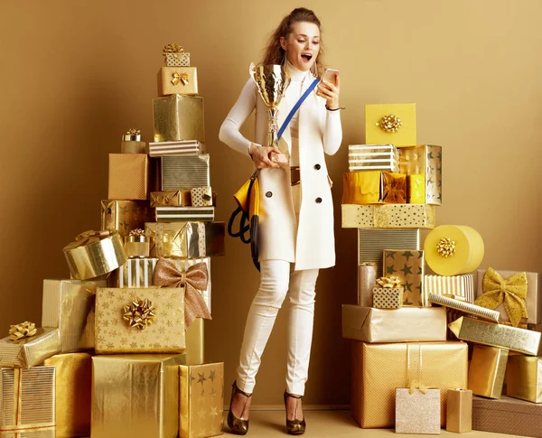 Shopper vrouw met gouden Goblet kijken naar smartphone — Stockfoto