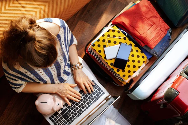 Stylish woman with piggy bank booking economy hotel online — Stock Photo, Image