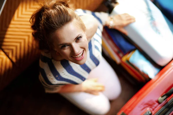 Sonriente joven mujer embalaje cosas en abierto viaje maleta —  Fotos de Stock