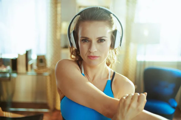 Sports woman listening to music with headphones and stretching — Stock Photo, Image