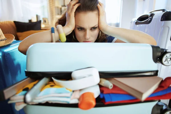 Stressed traveller woman trying to close over packed suitcase — Stock Photo, Image