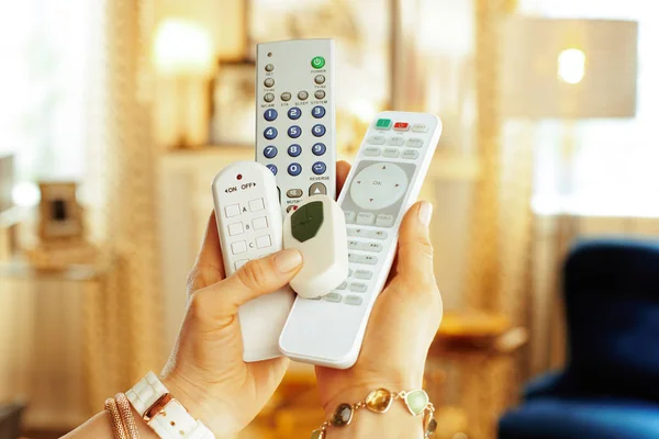 Closeup on remote controls in hands of modern woman — Stock Photo, Image