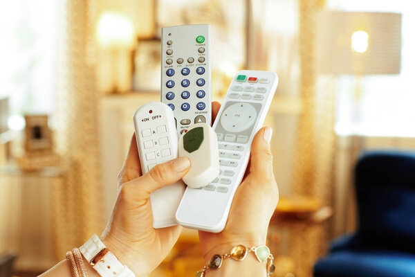 Closeup on remote controls in hands of modern woman
