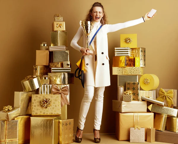 Happy shopper woman with smartphone and golden goblet rejoicing — Stock Photo, Image