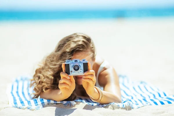 Closeup on photo camera holding by woman laying on towel — Stock Photo, Image