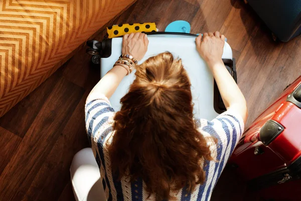Young woman closing over packed suitcase — Stock Photo, Image