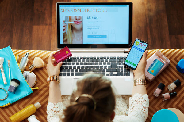 woman with credit card buying cosmetics online on laptop
