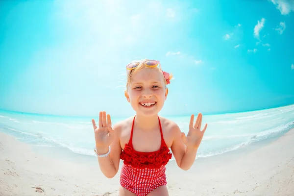 Menina sorridente no litoral apresentando algo na palma da mão vazia — Fotografia de Stock