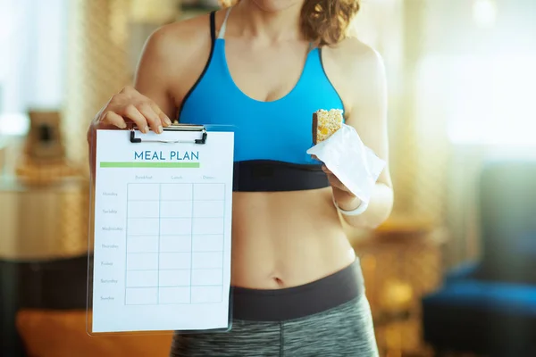 Primer plano de la mujer con barra de fitness que muestra el plan de comidas —  Fotos de Stock