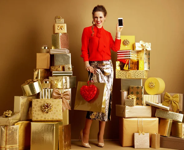 Fashion-monger con shopping bag e cuore rosso che mostra il cellulare — Foto Stock