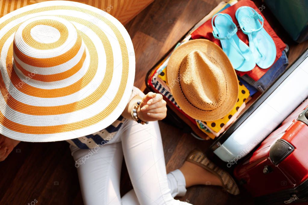 modern woman with big summer hat packing for summer holiday
