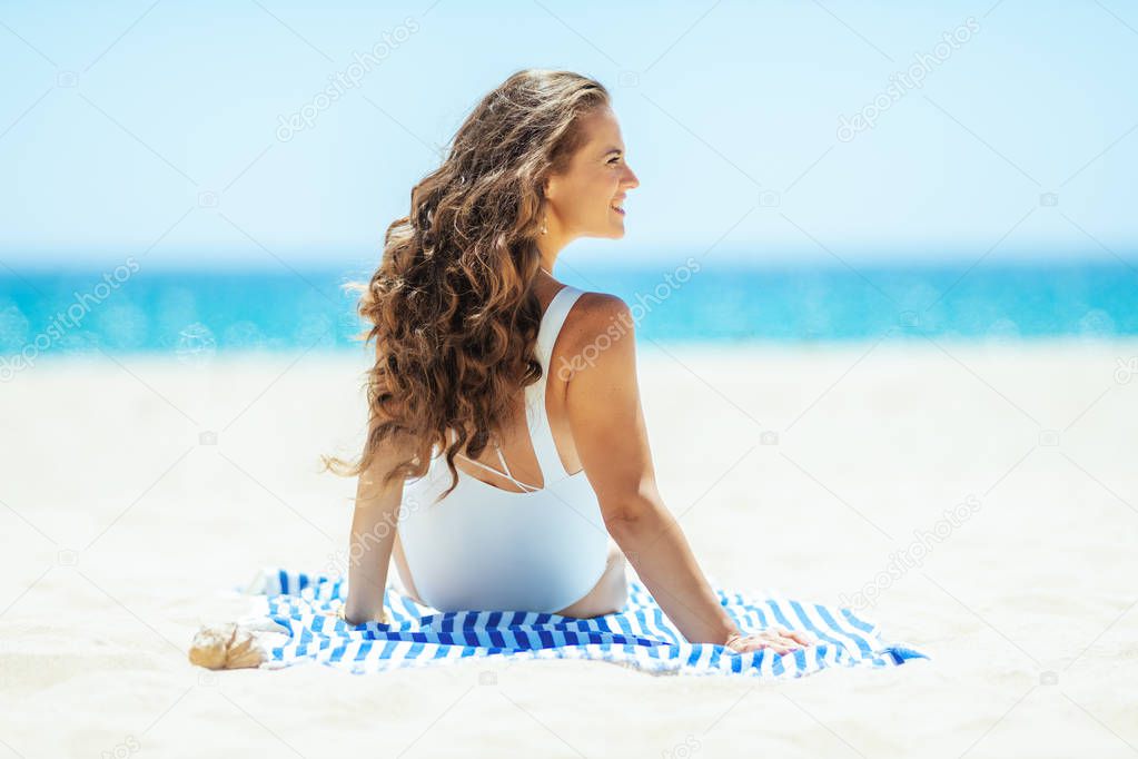 woman siting on a striped towel and looking aside