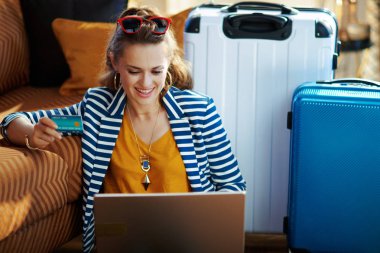 dizüstü bilgisayarda kredi kartı rezervasyon biletleri ile gülümseyen trendy kadın