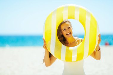 okyanus kıyısında kadın sarı şişme lifebuoy bakarak