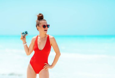 sahilde retro fotoğraf kamerası ile gülümseyen modern kadın