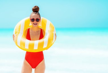 sarı şişme lifebuoy giyen deniz kıyısında gülümseyen kadın
