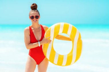 deniz kıyısında sarı şişme lifebuoy ile gülümseyen genç kadın