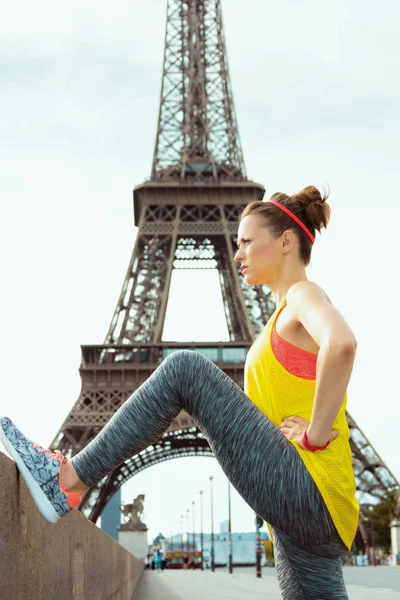 Mujer deportiva no muy lejos de la torre Eiffel estiramiento — Foto de Stock