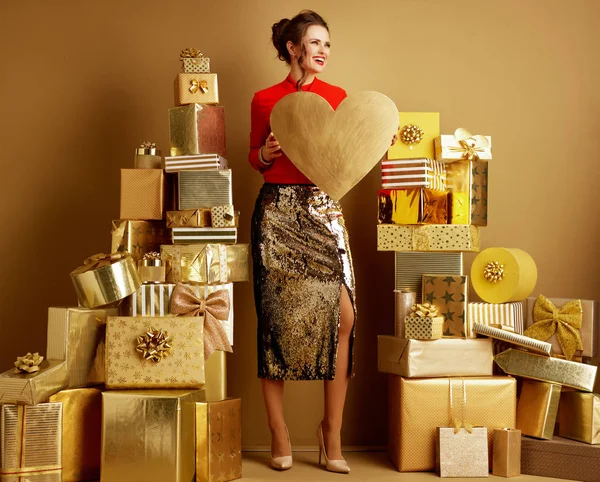 Leende ung shopper kvinna med gyllene hjärta ser åt sidan — Stockfoto