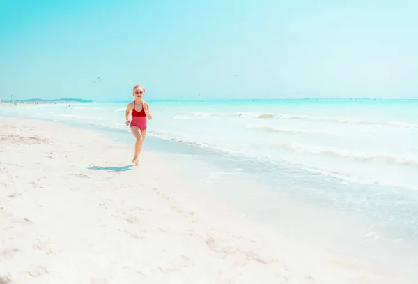 Chica moderna en traje de baño rojo en la orilla del mar trotando —  Fotos de Stock