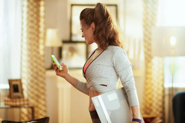 Sports woman with smart scale tracking weight in a fitness app — Stock Photo, Image