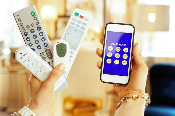 Closeup on remote controls and smartphone with smart home app — Stock Photo, Image