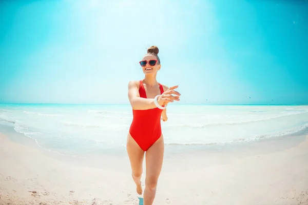 Ευτυχισμένη μοντέρνα γυναίκα με κόκκινα ρούχα παραλίας στην παραλία έχοντας χρόνο διασκέδασης — Φωτογραφία Αρχείου
