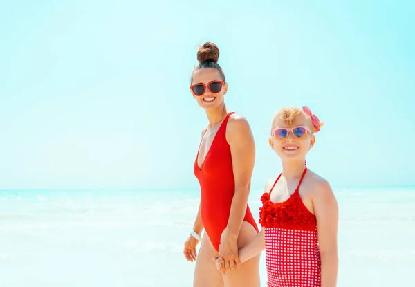 Mãe moderna feliz e criança em beachwear vermelho no litoral — Fotografia de Stock