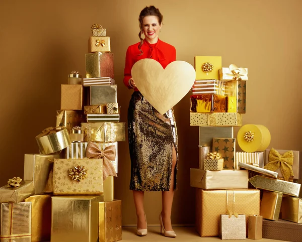 Mujer entre 2 pilas de regalos de oro que muestran el corazón de oro —  Fotos de Stock