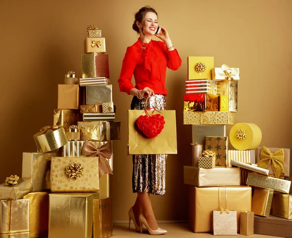 Šťastná žena s nákupním pytlem a červeným srdcem pomocí mobilního telefonu — Stock fotografie