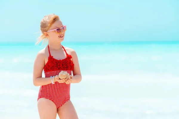 Glücklich modernes Mädchen mit Muschel Blick in die Ferne am Strand — Stockfoto