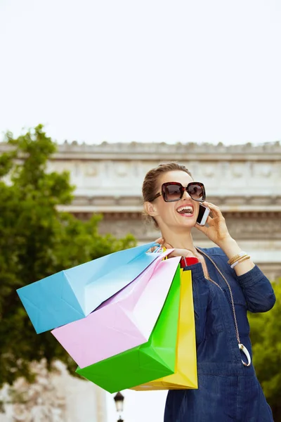 Leende fashion-monger med shoppingväskor pratar på mobiltelefon — Stockfoto