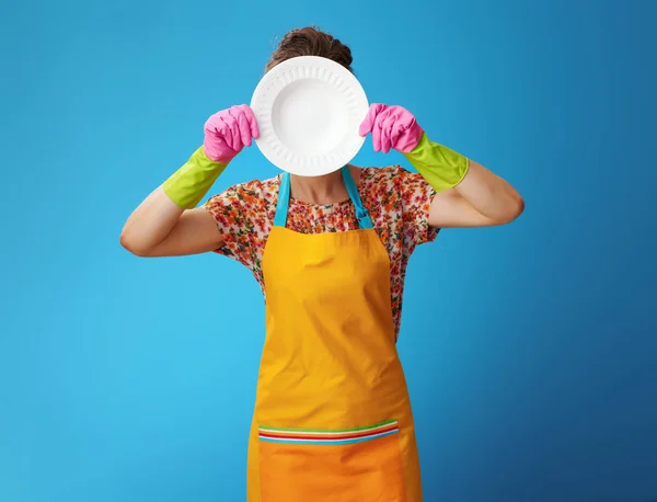 Jonge vrouw Holding gewassen plaat voor gezicht op blauw — Stockfoto