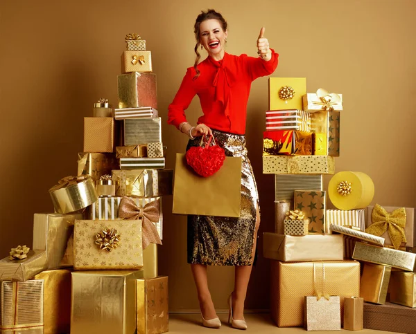 Donna sorridente con shopping bag e cuore rosso mostrando pollici in su — Foto Stock