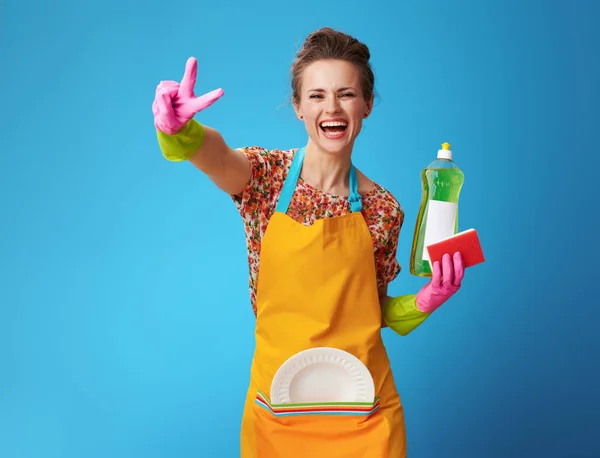 Housewife with sponge and dishwashing detergent showing victory — Stock Photo, Image