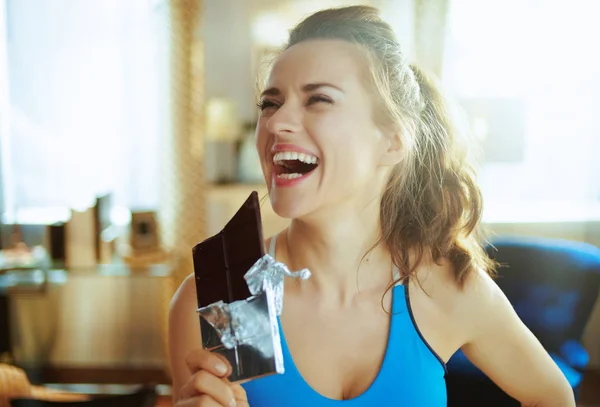 Щаслива активна жінка з шоколадним баром у сучасній вітальні — стокове фото