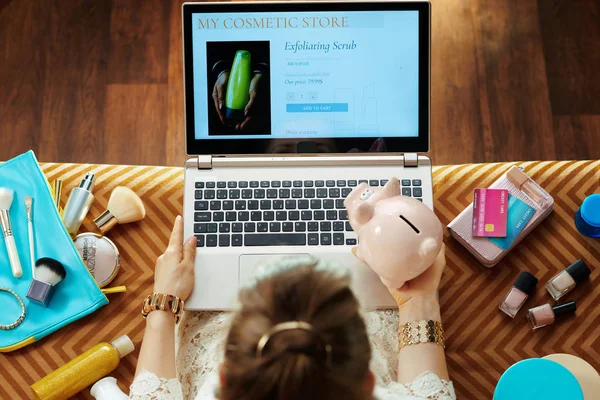 Ama de casa comprar en línea en el ordenador portátil y la celebración de alcancía — Foto de Stock