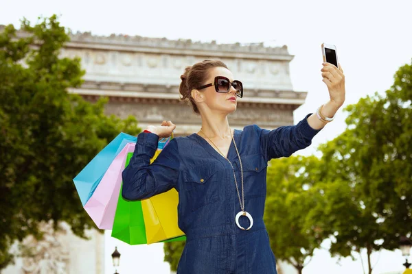 スマートフォンで自分撮りを取る買い物袋を持つ女性 — ストック写真
