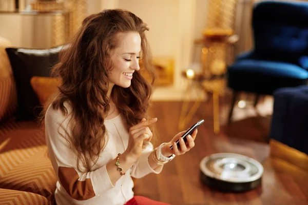 Femme au foyer en utilisant une application de maison intelligente sur smartphone et robot v — Photo