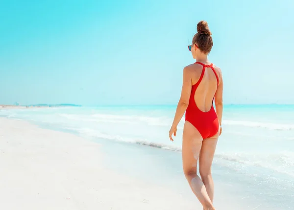 Moderne vrouw in rood badpak op Seacoast wandelen — Stockfoto