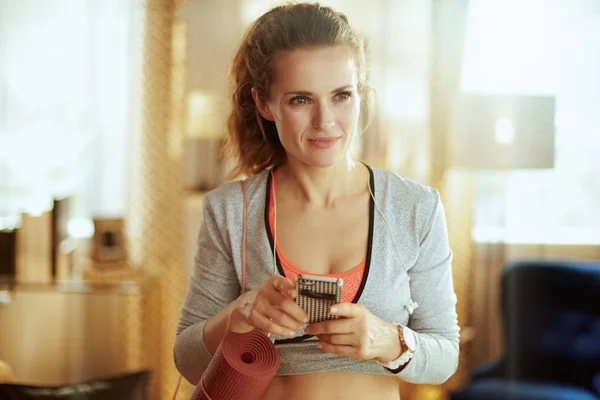 Mujer deportiva utilizando el servicio de entrenador de fitness en línea en el teléfono inteligente — Foto de Stock